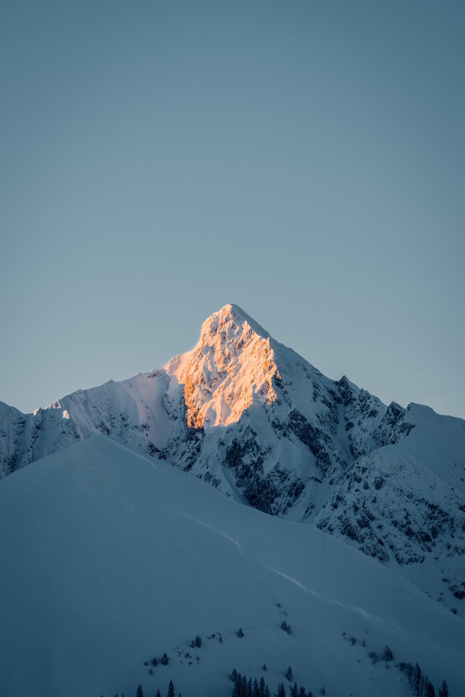 A sunlit mountain peak above a snowy landscape